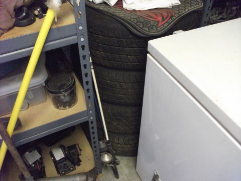 1994 Ford Probe - A cluttered garage scene shows stacked tires, storage shelves with various items, and a large white appliance.