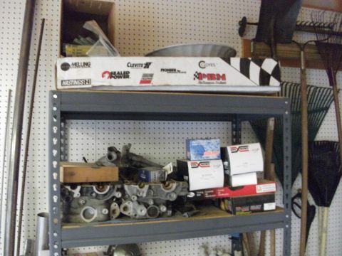 1994 Ford Probe - Shelving unit holds engine components and various automotive part boxes. Rakes and shovels hang on the wall.