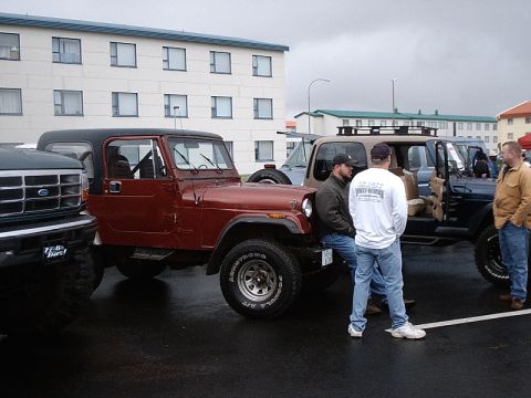 1996 Ford Bronco - Several Jeeps and a Ford truck are parked together on a cloudy day, with people gathered around.