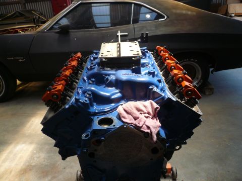 1975 Ford Ranchero - A blue engine sits in front of a black 1970s car.