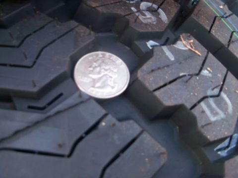 1989 Ford Bronco - A quarter is placed on a tire tread, likely to show tread depth.