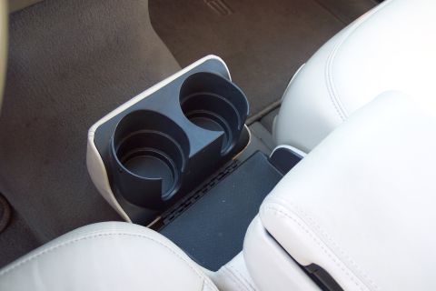 2001 Ford Crown Victoria - The interior of a vehicle shows a center console with dual cup holders and a closed armrest compartment.