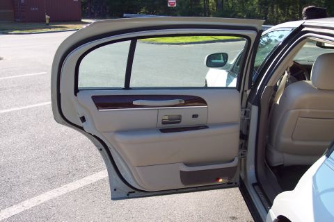 2001 Ford Crown Victoria - The interior of a white Lincoln Town Car shows tan leather seats and wood trim details.