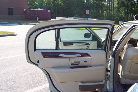 2001 Ford Crown Victoria - The interior of a beige sedan is visible with the rear passenger door and front passenger door ajar.