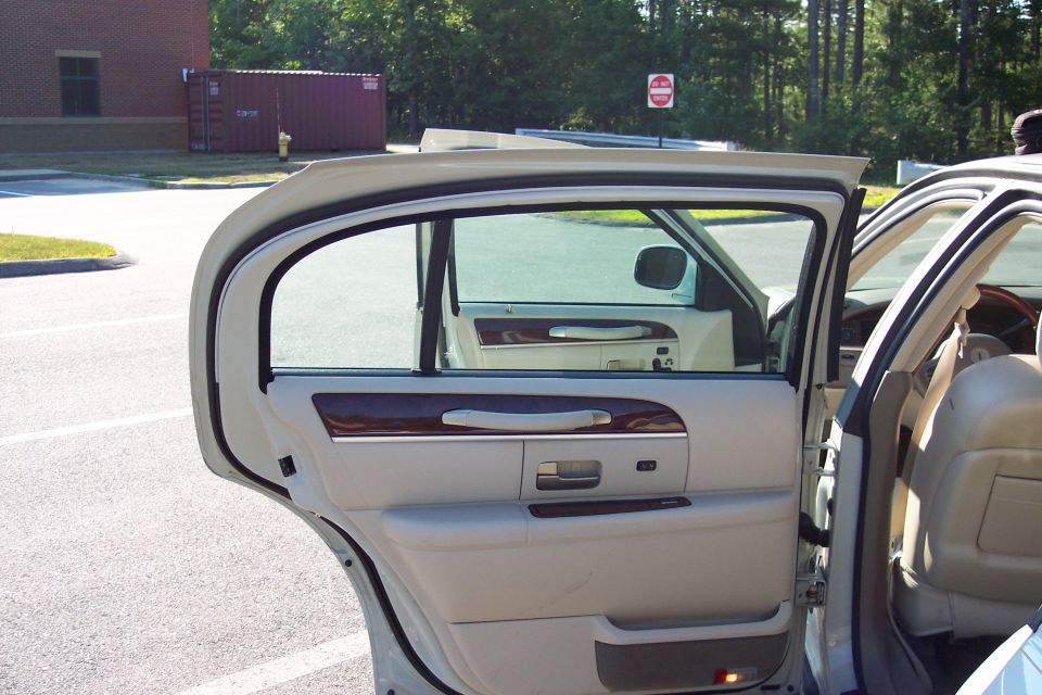 Interior view of a beige sedan's open rear door and front passenger door
