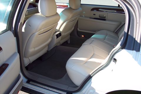 2001 Ford Crown Victoria - The interior of a Lincoln Town Car shows beige leather seats and wood trim.