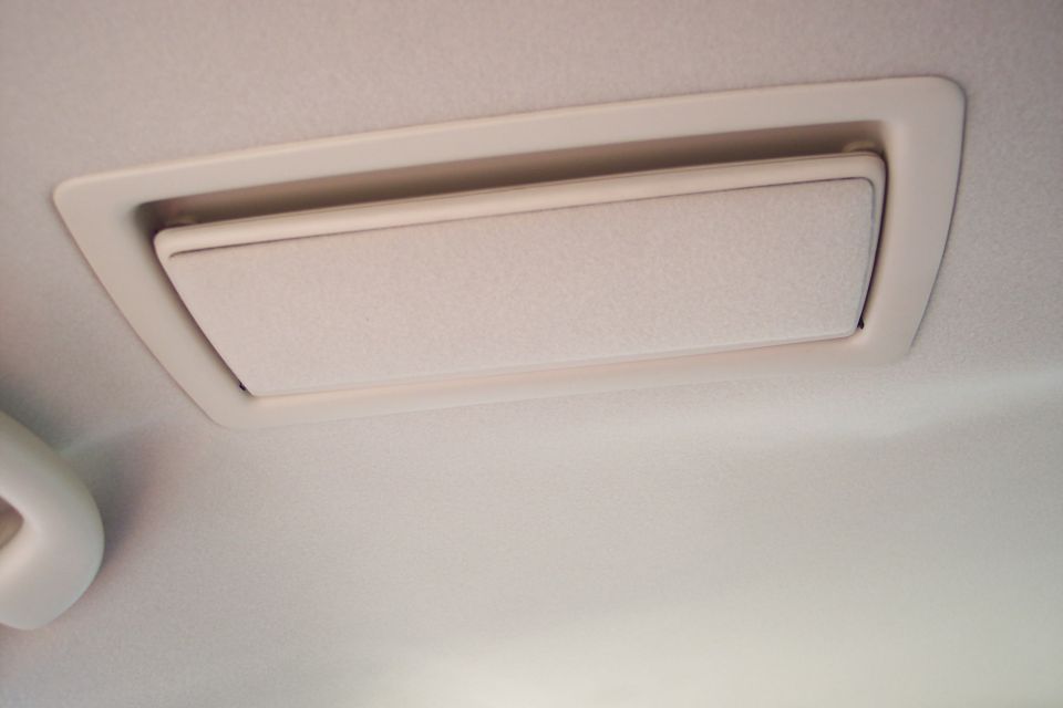 Interior ceiling vent with beige trim against a light-colored headliner