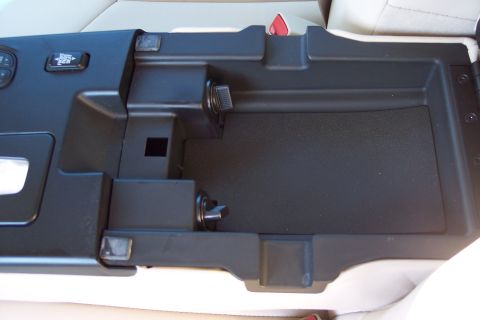 2001 Ford Crown Victoria - The interior of a vehicle's center console storage compartment is shown, a button and power outlets.
