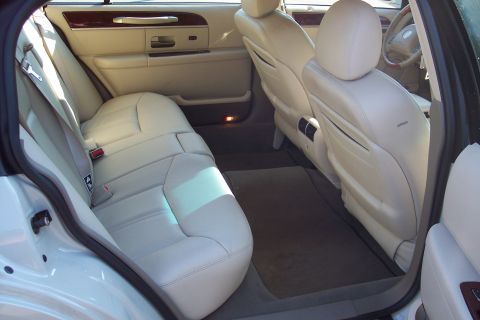 2001 Ford Crown Victoria - The interior of a Lincoln Town Car features beige leather seats and wood trim accents.