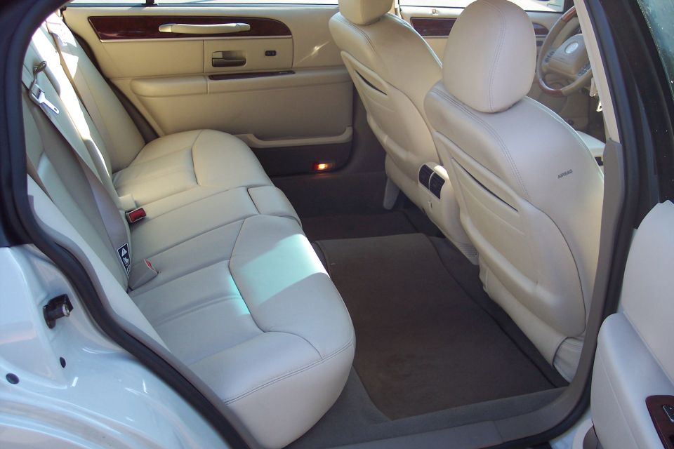 Interior of a white Lincoln Town Car, showing beige leather seats, door panel, and dashboard