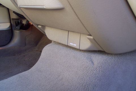 2001 Ford Crown Victoria - The interior of a car shows a tan panel with a power outlet labeled.