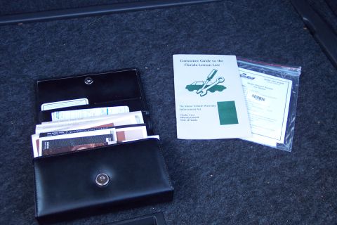 2001 Ford Crown Victoria - Vehicle documents including a Florida Lemon Law guide and owner's manual are organized in a wallet and bag.