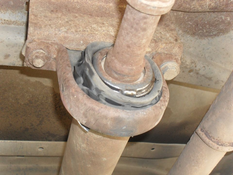 Close-up of a rusty driveshaft carrier bearing mount on a vehicle's undercarriage