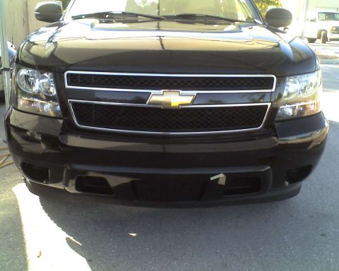1993 Ford C-350 (Centurion Conversions) - Front view of a black Chevrolet Tahoe, showing its grille and headlights.