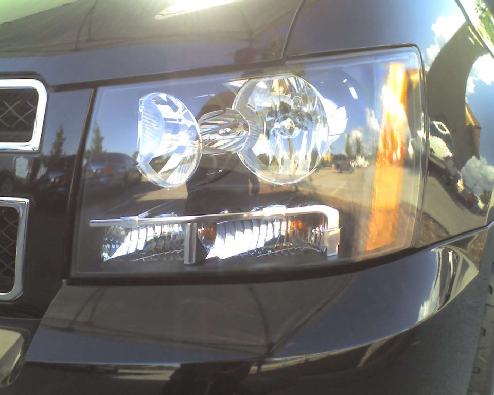 Close-up of a clear composite headlight and amber turn signal on a black truck