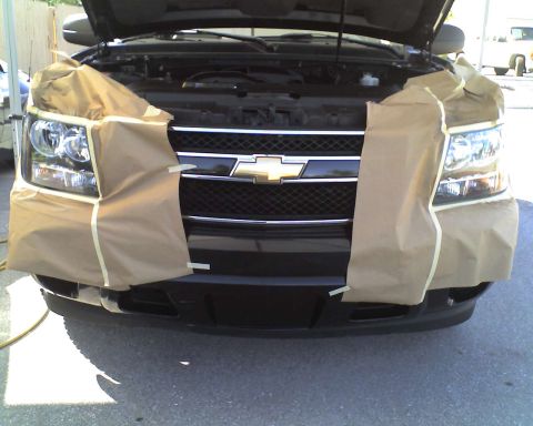 1993 Ford C-350 (Centurion Conversions) - The front of a black Chevrolet SUV is covered in masking paper, with the hood open, revealing the engine bay.