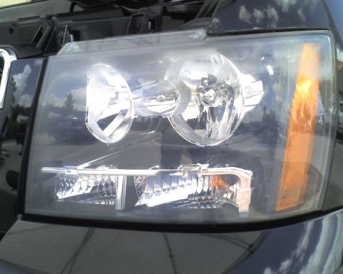 1993 Ford C-350 (Centurion Conversions) - Headlight assembly detail on a vehicle, with reflections of clouds in the lens.