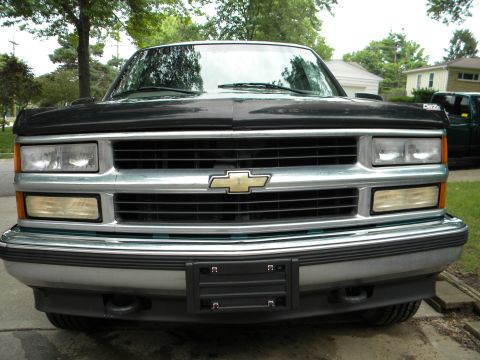 1999 Chevrolet Suburban - Front view of a black 1999 Chevrolet Suburban, highlighting its chrome grille and headlights.