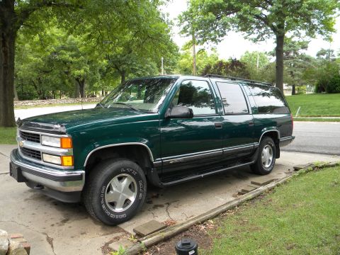 1999 Chevrolet Suburban - This 1999 Chevrolet Suburban is parked on a concrete driveway, with trees and grass surrounding it.