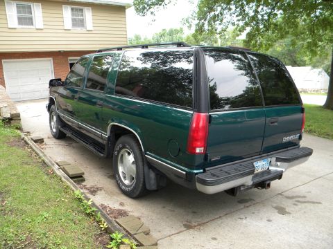 1999 Chevrolet Suburban - Rear view of a dark green 1999 Chevrolet Suburban parked in a driveway next to a house.