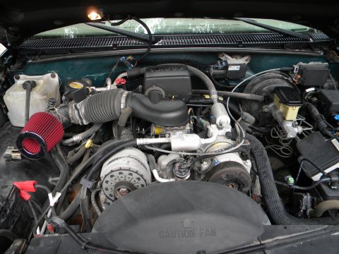 1999 Chevrolet Suburban - The engine bay of a vehicle is shown, an aftermarket air intake system and other engine components.