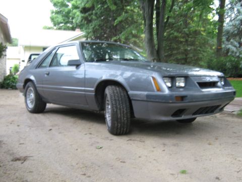 1985 Ford Mustang - Gray 1985 Ford Mustang hatchback parked outside a house.
