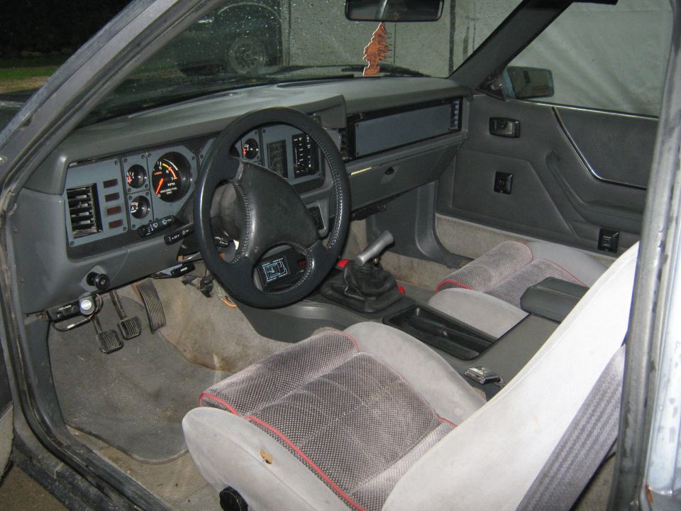 1985 Ford Mustang interior showing dashboard, steering wheel, seats, and gear shifter