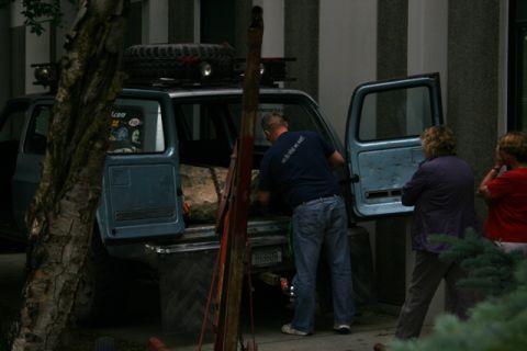 1990 Chevrolet Suburban - People load cargo into a blue 1990 Chevrolet Suburban, which has a spare tire mounted on its roof rack.