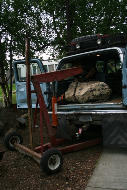 1990 Chevrolet Suburban - A blue 1990 Chevrolet Suburban is shown from the rear as a rock is being loaded into its cargo area using an engine hoist.