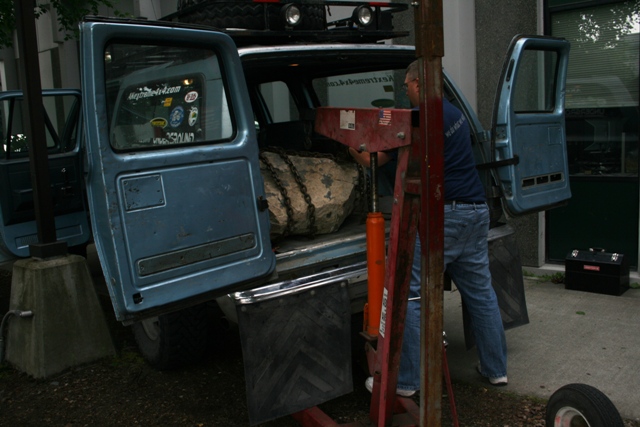 Blue 1990 Chevrolet Suburban with rear doors open, loading a large rock with chains