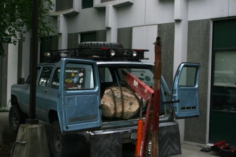1990 Chevrolet Suburban - This 1990 Chevrolet Suburban is equipped with a roof rack, a crane, and is loaded with a large rock.