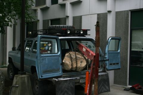 1990 Chevrolet Suburban - 1990 Chevrolet Suburban being loaded with a large rock using a crane. Spare tire and roof rack are visible.