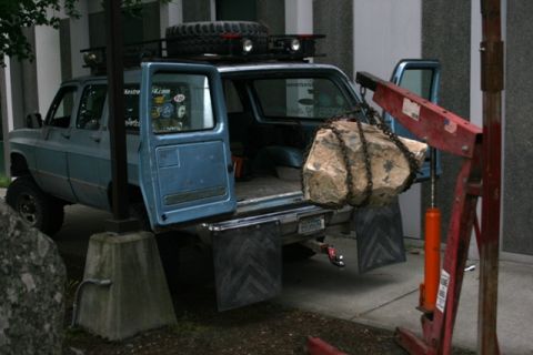 1990 Chevrolet Suburban - A blue 1990 Chevrolet Suburban is shown with its doors open as a rock is lifted from its cargo area.