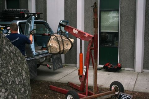 1990 Chevrolet Suburban - Engine hoist lifting a large rock into the bed of a pickup truck.