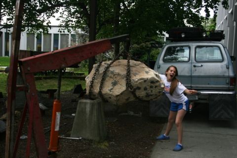 1990 Chevrolet Suburban - A girl stands next to a van as a large rock is lifted by a crane.