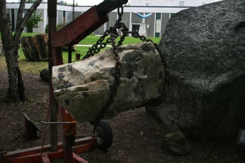 1990 Chevrolet Suburban - A large rock is being hoisted by a crane, suggesting a landscaping or construction project.
