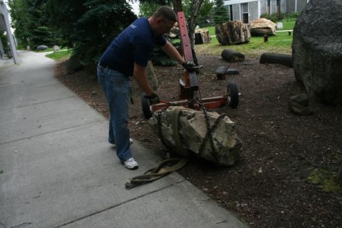 1990 Chevrolet Suburban - Man uses trolley jack to move a large rock, with other rocks and trees in the background.