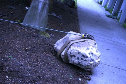 1990 Chevrolet Suburban - A large rock is being moved with straps and a cable, secured to a concrete pillar.