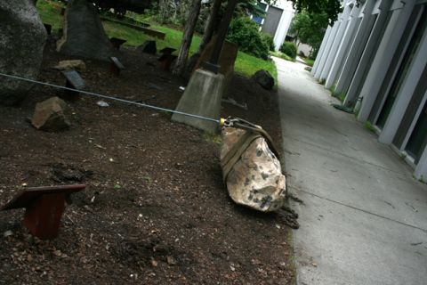 1990 Chevrolet Suburban - A rock is being moved using a strap and cable, positioned next to a building's walkway.