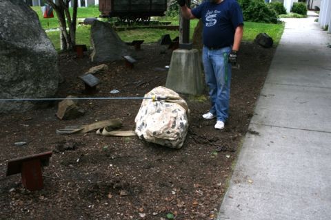 1990 Chevrolet Suburban - Man supervises the movement of a large rock with chains and straps in an outdoor area.