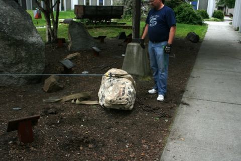1990 Chevrolet Suburban - A man stands near a large rock in a garden setting, with straps and chains visible on the ground.