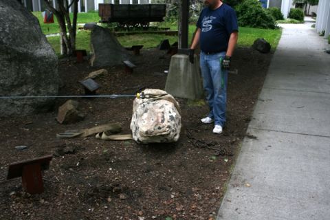 1990 Chevrolet Suburban - A man stands near a large rock, with straps and chains visible on the ground around it.