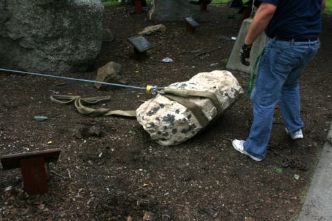 1990 Chevrolet Suburban - A person assists in moving a large rock with straps and a cable in a garden setting.