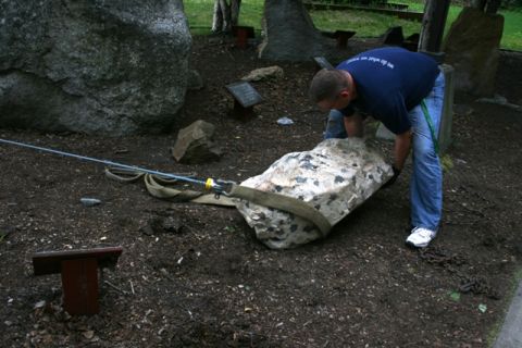 1990 Chevrolet Suburban - Man uses a strap and cable to move a large rock in an outdoor setting.