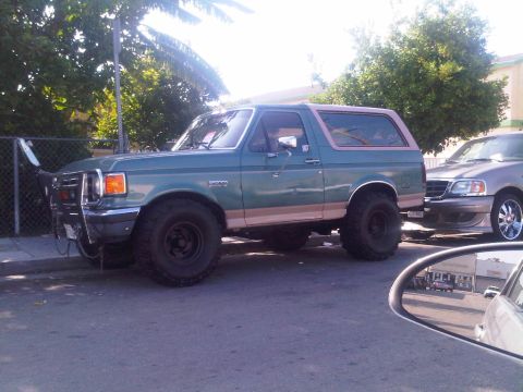 1986 Ford Bronco - This 1986 Ford Bronco is seen parked on a street next to another vehicle.