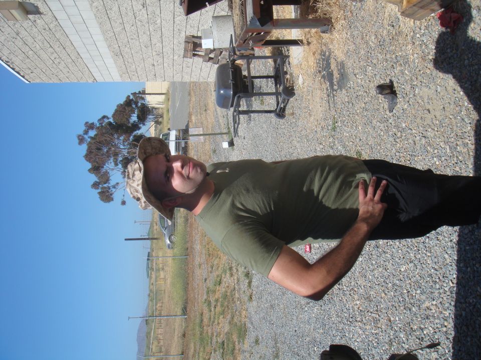 Man in camouflage hat and green t-shirt poses outdoors