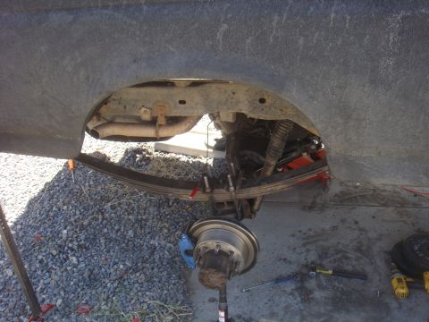 Rear axle assembly with leaf spring, shock absorber, and brake rotor visible