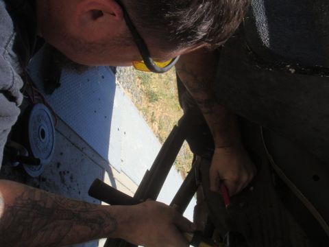 Mechanic working on vehicle frame with Supermotors.net logo visible
