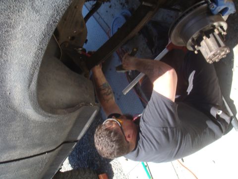 Mechanic working on the suspension and brake assembly of a vehicle. The wheel hub is visible