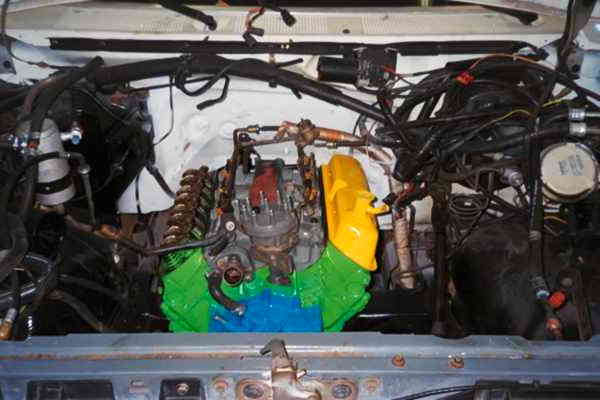 Engine bay with bare wiring harness, distributor and valley painted green, yellow and blue